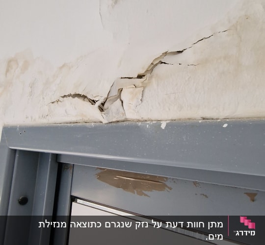 קיר עם סדקים מעל דלת מתכת אפורה